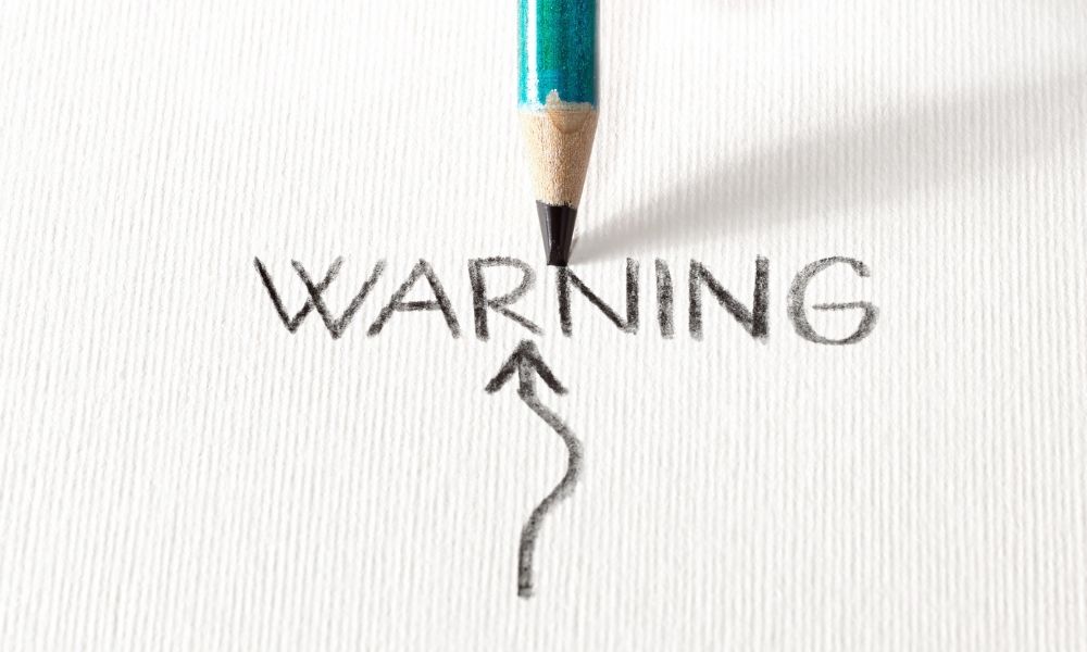 warning written by a pencil on paper about website designer red flags to watch out for